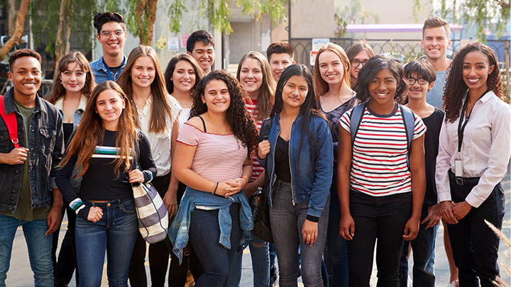male and female college students outside of campus building posing for a picture
